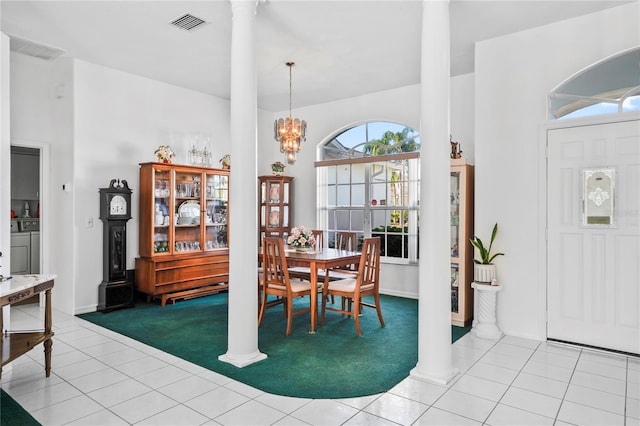 tiled dining room featuring a notable chandelier, ornate columns, and washing machine and clothes dryer