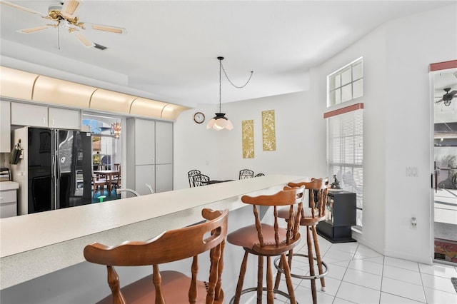 kitchen featuring black fridge, plenty of natural light, ceiling fan, and decorative light fixtures