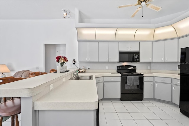 kitchen featuring sink, kitchen peninsula, a breakfast bar, white cabinets, and black appliances