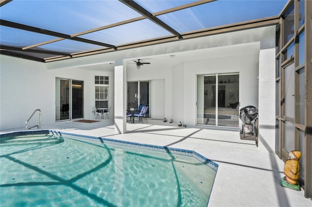 view of swimming pool featuring a patio, glass enclosure, and ceiling fan