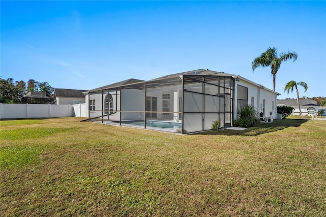 rear view of house with a lanai, a yard, and a fenced in pool