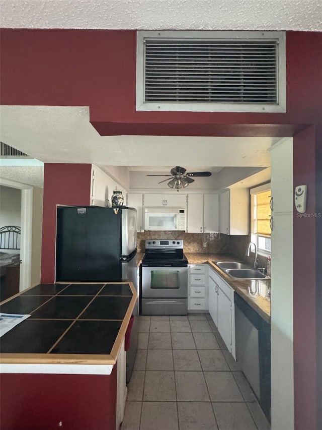 kitchen with white cabinetry, sink, backsplash, light tile patterned floors, and appliances with stainless steel finishes