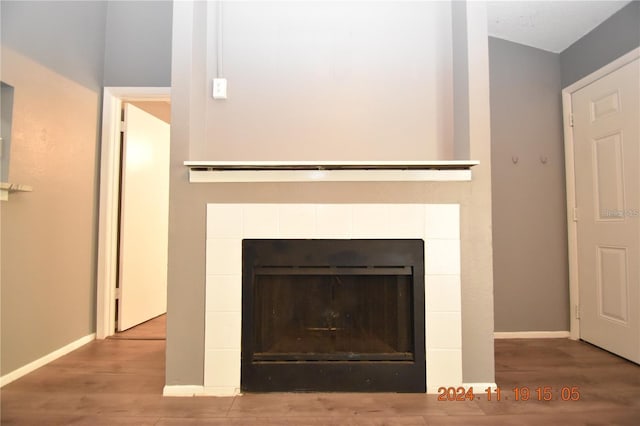 room details featuring wood-type flooring and a tile fireplace