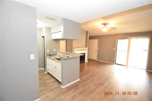 kitchen featuring ceiling fan, light stone countertops, light wood-type flooring, a textured ceiling, and white cabinetry