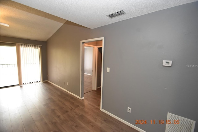 spare room featuring a textured ceiling, dark hardwood / wood-style flooring, and vaulted ceiling