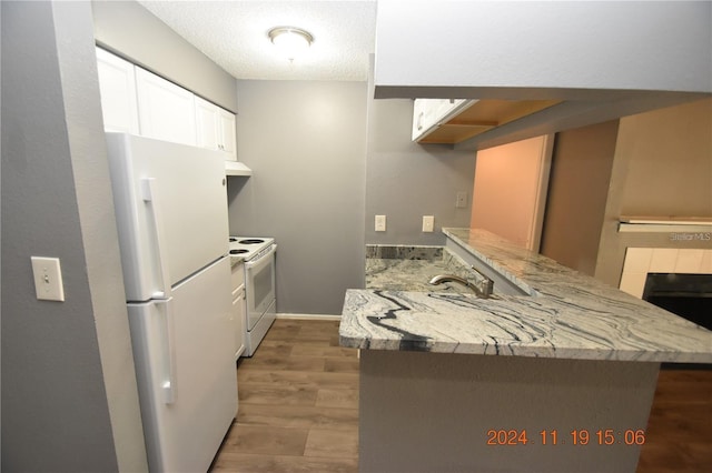 kitchen with range hood, dark hardwood / wood-style floors, kitchen peninsula, white appliances, and white cabinets