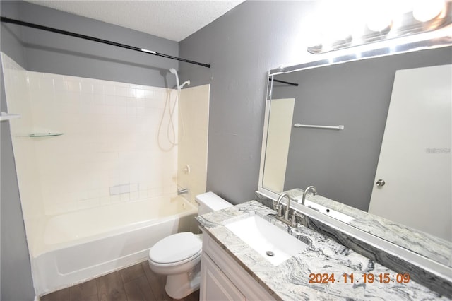 full bathroom with hardwood / wood-style floors, vanity, shower / tub combination, toilet, and a textured ceiling