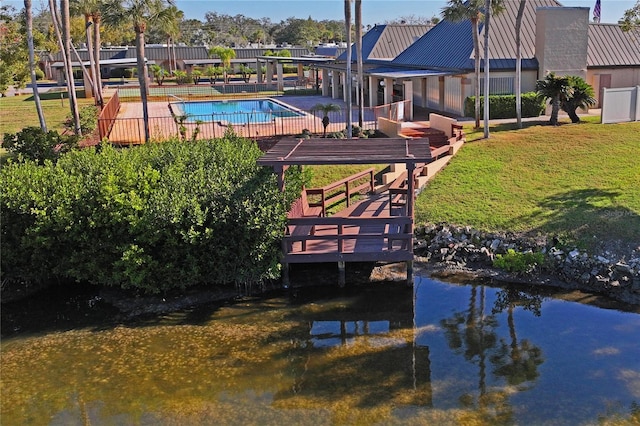 dock area with a water view, a fenced in pool, and a lawn