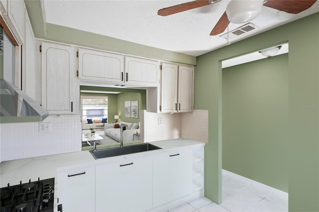 kitchen featuring ceiling fan, light tile patterned floors, a textured ceiling, white cabinetry, and gas cooktop