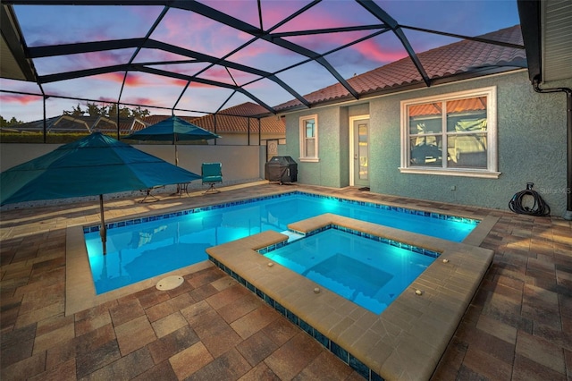 pool at dusk featuring a grill, a lanai, an in ground hot tub, and a patio