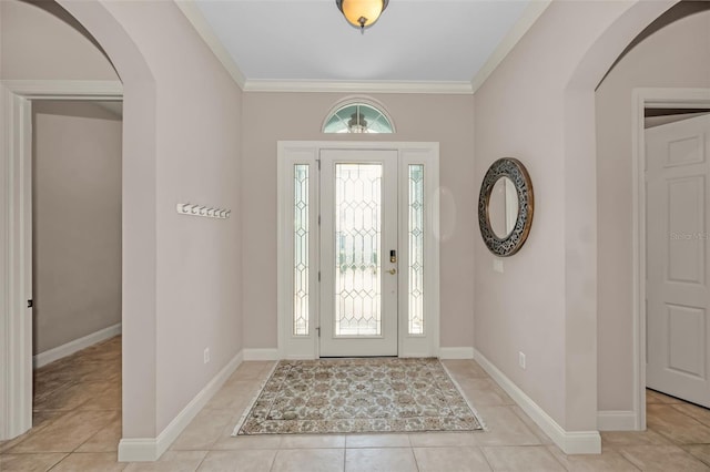 foyer entrance featuring arched walkways, ornamental molding, light tile patterned floors, and baseboards