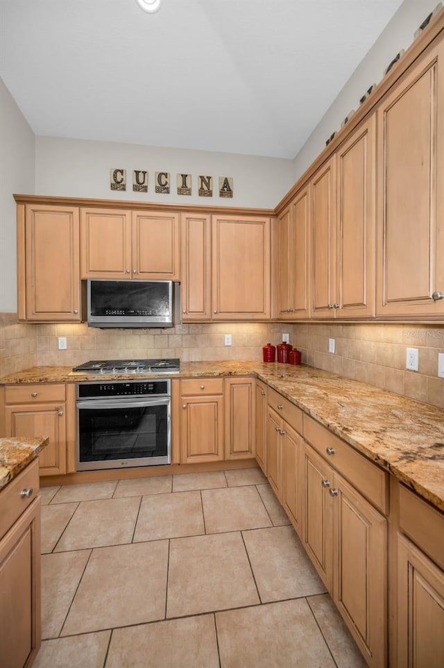 kitchen featuring light tile patterned floors, appliances with stainless steel finishes, backsplash, and light stone counters