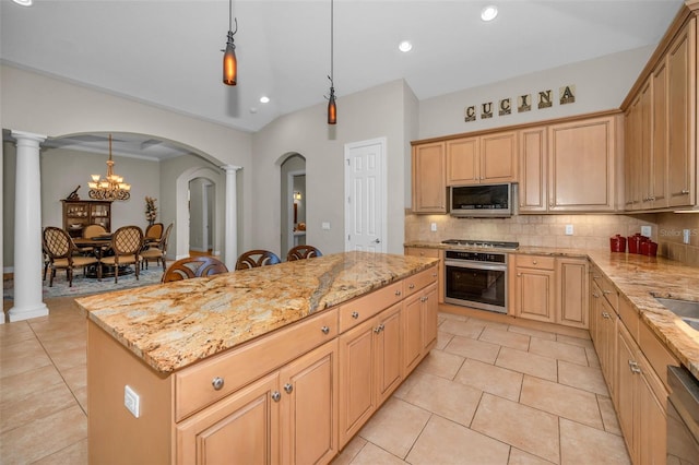 kitchen with arched walkways, stainless steel appliances, backsplash, a kitchen island, and ornate columns