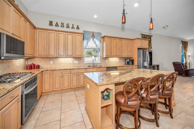 kitchen featuring light stone counters, decorative backsplash, appliances with stainless steel finishes, a sink, and a kitchen island