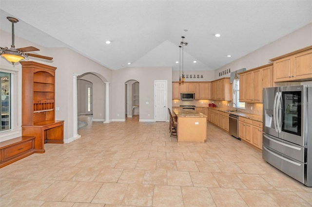 kitchen with arched walkways, a center island, stainless steel appliances, vaulted ceiling, and a sink