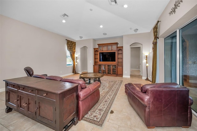 living room with arched walkways, visible vents, baseboards, and recessed lighting