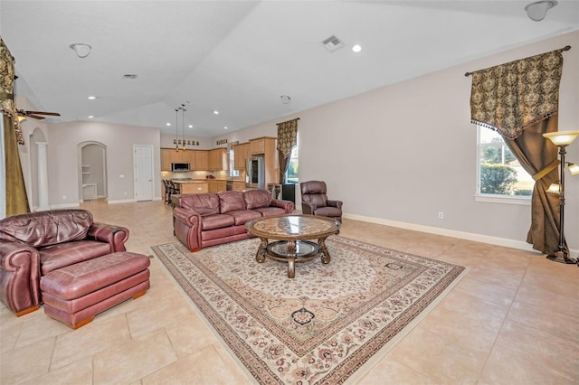 living area featuring lofted ceiling, visible vents, arched walkways, and baseboards