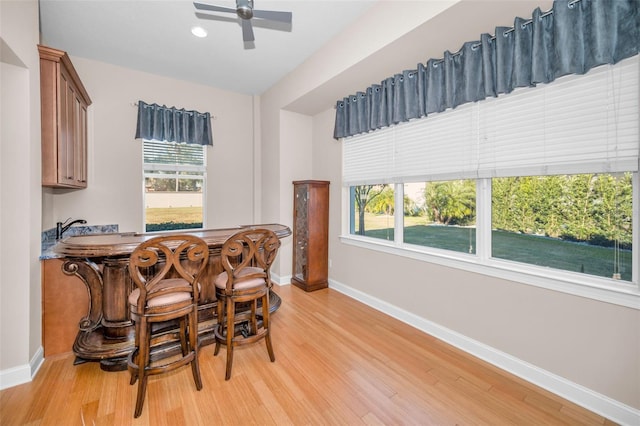 dining area featuring light wood-style floors, a wealth of natural light, ceiling fan, and baseboards