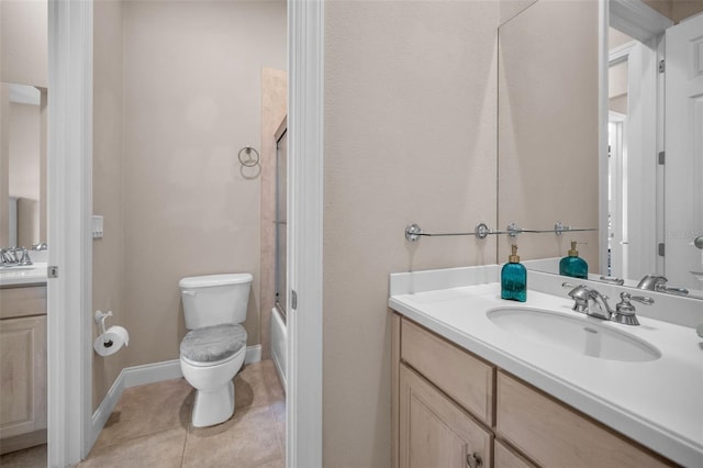 bathroom with baseboards, toilet, enclosed tub / shower combo, tile patterned floors, and vanity