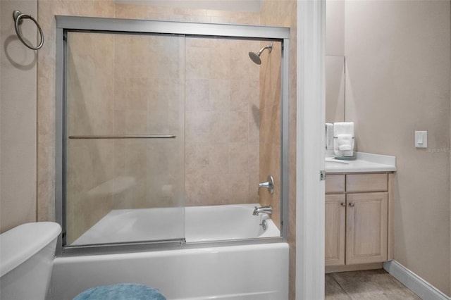 bathroom featuring bath / shower combo with glass door, vanity, toilet, and baseboards