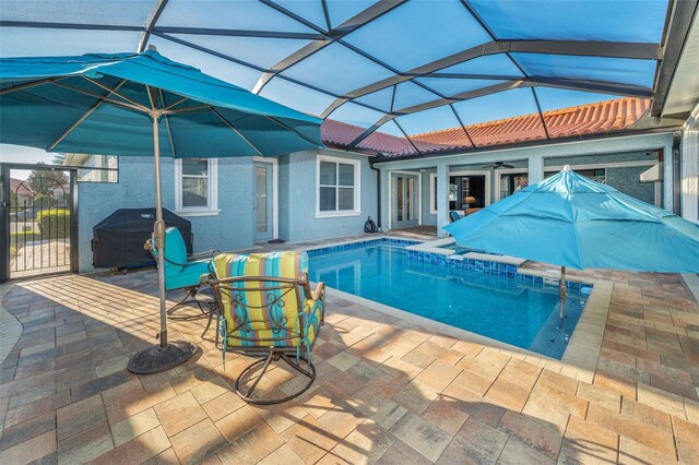 outdoor pool featuring a patio, a grill, glass enclosure, and a ceiling fan