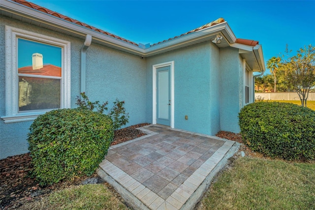 doorway to property with a patio area, fence, and stucco siding