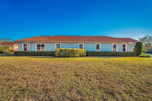 single story home featuring stucco siding, a front lawn, and a tiled roof