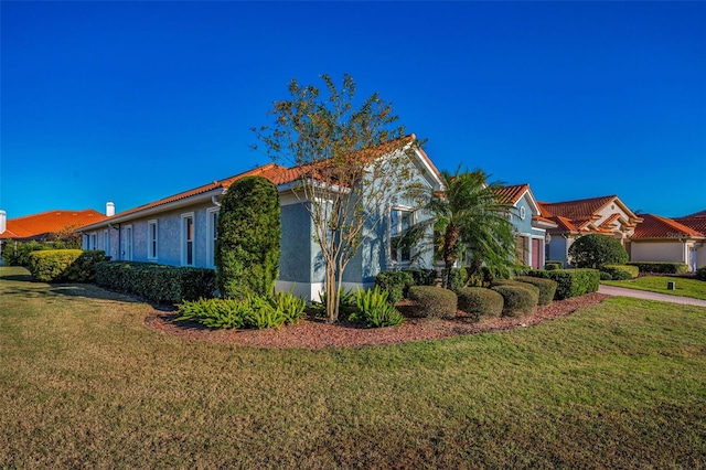 view of side of property with a garage, a yard, driveway, and stucco siding