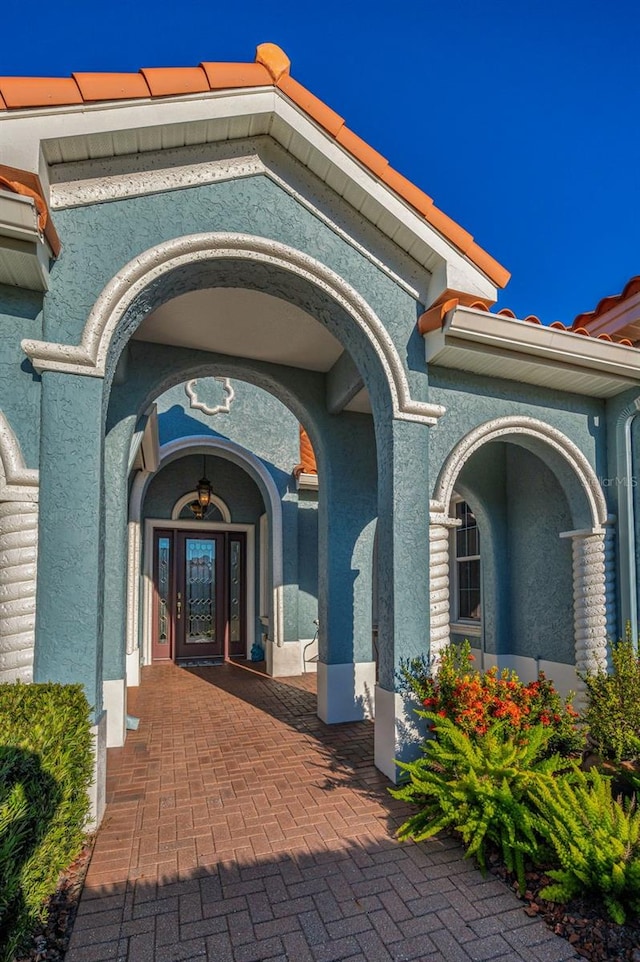 entrance to property with a tile roof and stucco siding