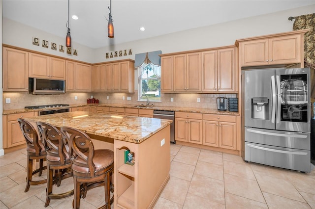 kitchen featuring decorative backsplash, a kitchen island, light stone countertops, stainless steel appliances, and a sink