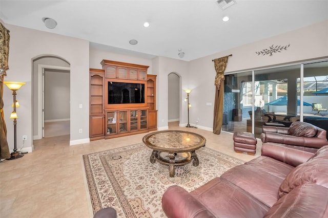 living area featuring arched walkways, baseboards, visible vents, and recessed lighting