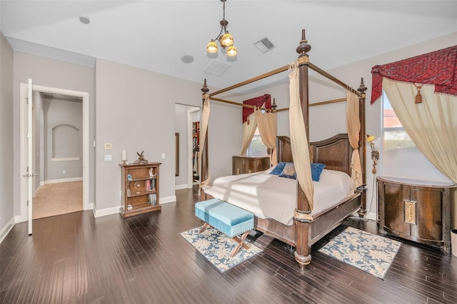 bedroom featuring an inviting chandelier, wood finished floors, visible vents, and baseboards