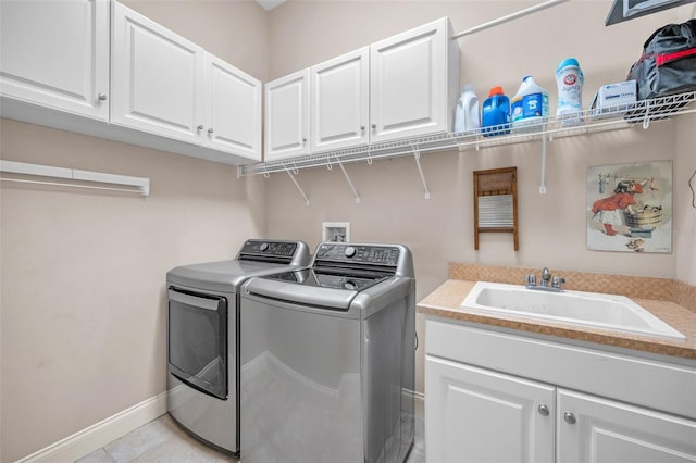 clothes washing area featuring cabinet space, washing machine and dryer, baseboards, and a sink