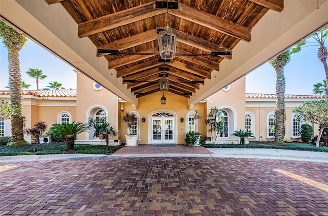 entrance to property with french doors, a tile roof, and stucco siding