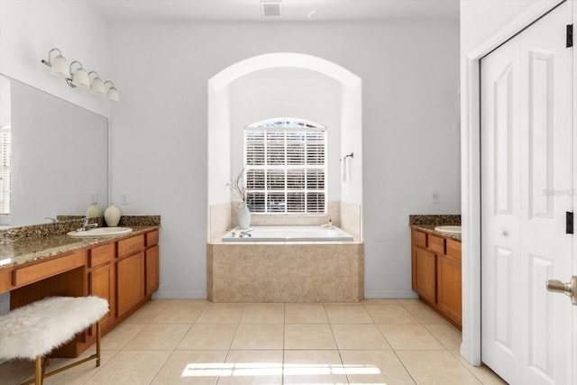 bathroom featuring tile patterned floors, vanity, and tiled tub