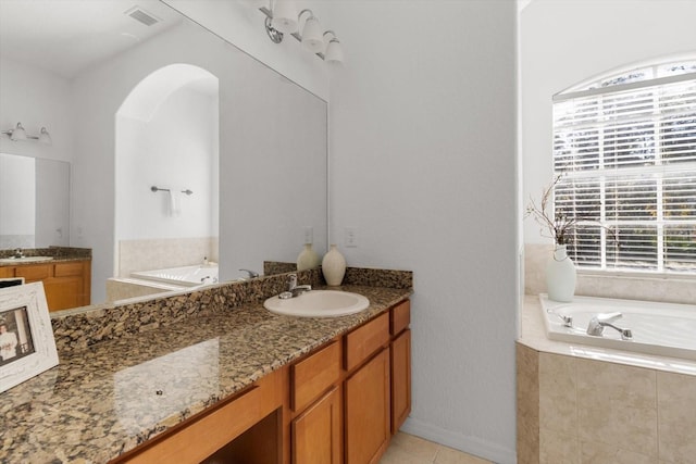 bathroom with tile patterned floors, vanity, and tiled bath