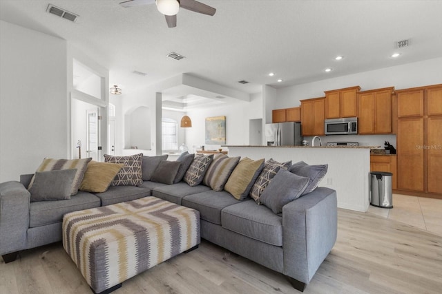 living room with light wood-type flooring and ceiling fan