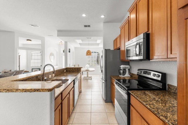 kitchen with stone counters, a center island with sink, sink, light tile patterned floors, and stainless steel appliances