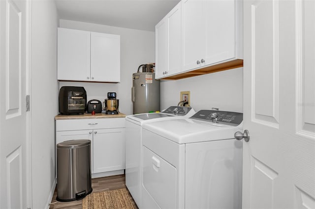 washroom featuring washing machine and clothes dryer, wood-type flooring, cabinets, and water heater