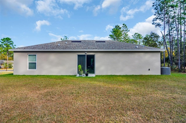 back of house with cooling unit and a lawn