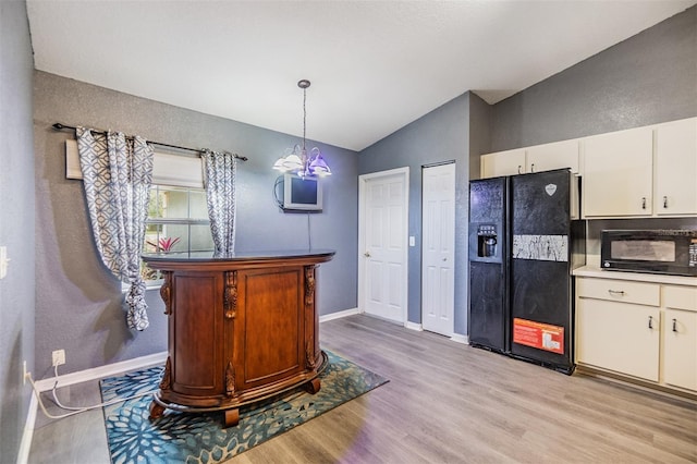 kitchen featuring lofted ceiling, black appliances, white cabinets, light hardwood / wood-style flooring, and decorative light fixtures