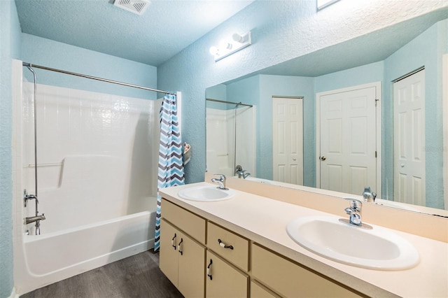 bathroom featuring hardwood / wood-style floors, shower / bath combination with curtain, a textured ceiling, and vanity