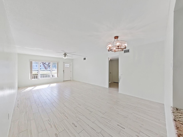 unfurnished living room with ceiling fan with notable chandelier and light hardwood / wood-style floors