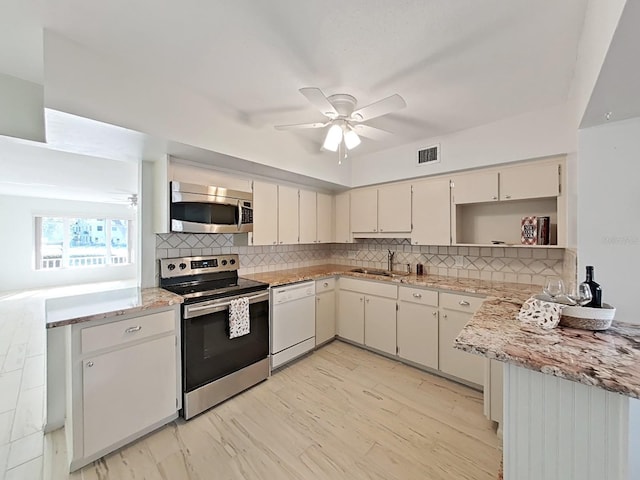 kitchen featuring ceiling fan, sink, stainless steel appliances, light stone counters, and decorative backsplash