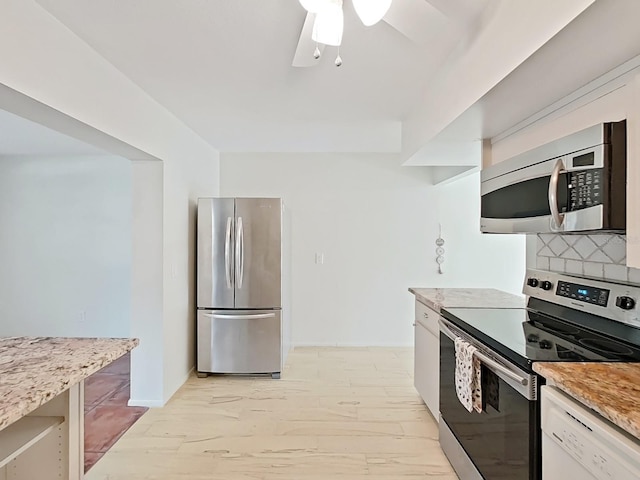 kitchen featuring tasteful backsplash, white cabinetry, stainless steel appliances, and light stone counters