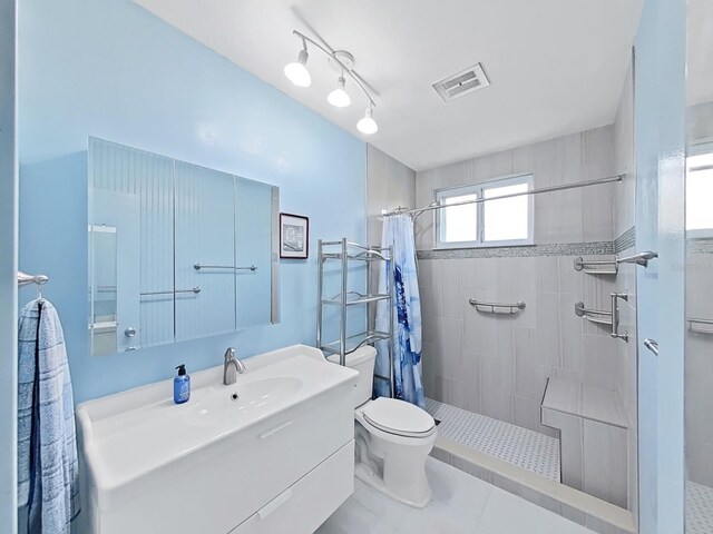 bathroom with a shower with shower curtain, tile patterned floors, vanity, and toilet