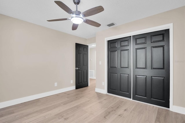 unfurnished bedroom featuring a closet, ceiling fan, light hardwood / wood-style flooring, and a textured ceiling