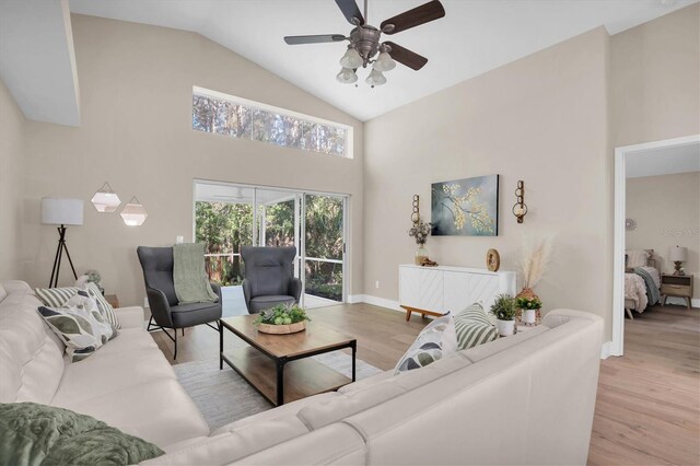 living room featuring ceiling fan, light wood-type flooring, and high vaulted ceiling