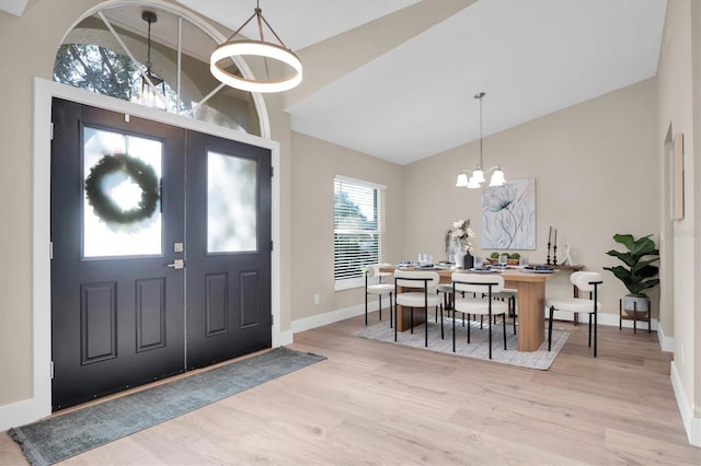 entrance foyer featuring light hardwood / wood-style flooring, high vaulted ceiling, and a chandelier