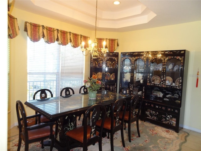 dining room featuring a raised ceiling, tile patterned flooring, and an inviting chandelier